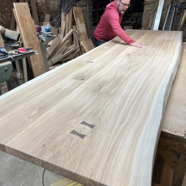 Ezra Harvey furniture maker giving the table a final fine sanding before the finish is applied